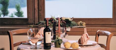 A table set for dining with a bottle of wine, glasses, a small plant, and pastries.