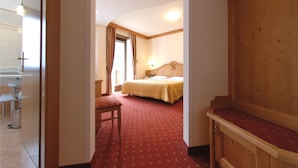 A hotel room with a bed, a desk, a chair, and a wooden wardrobe. - Hotel Ariston (Molveno)