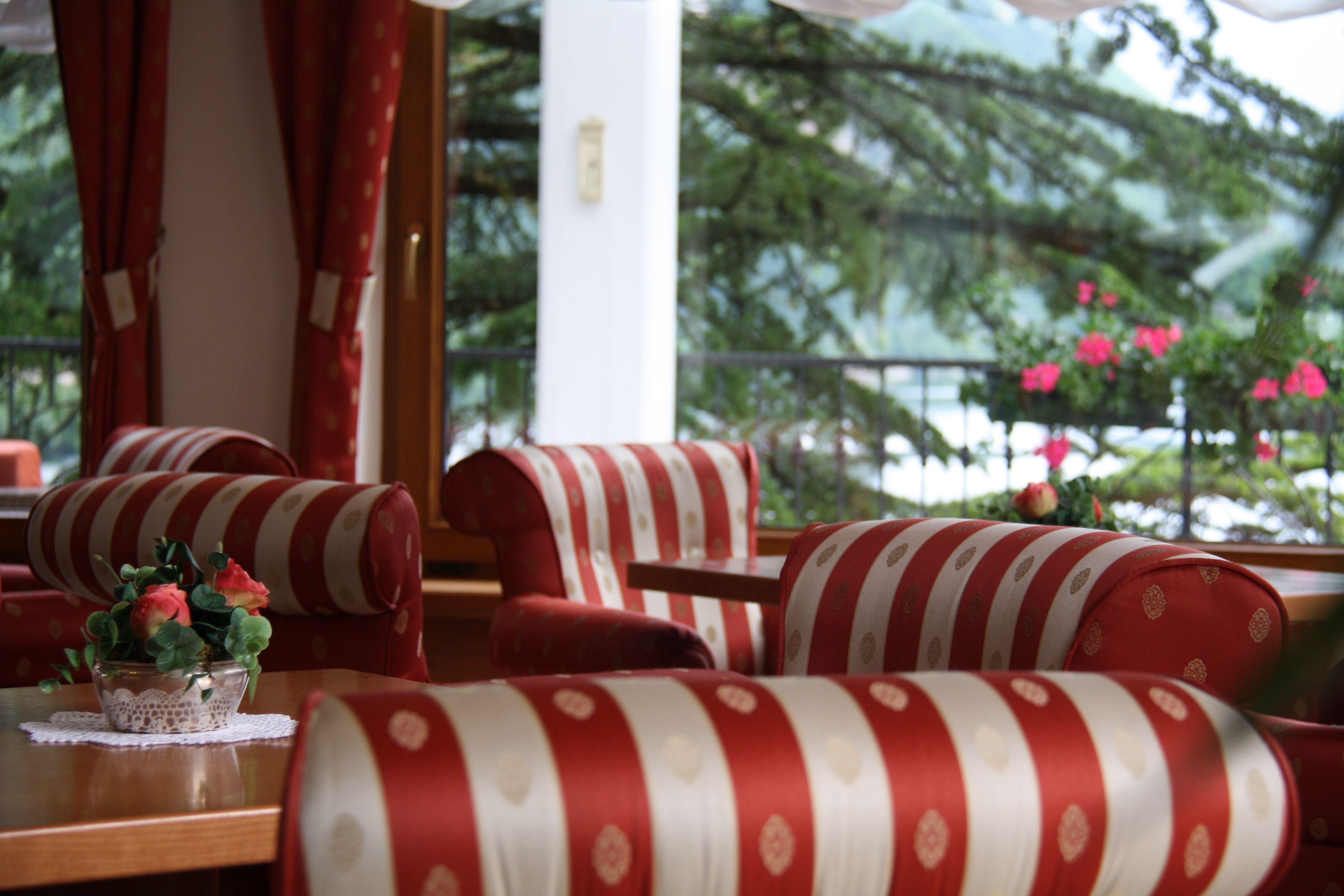 A seating area with striped red and white cushions, a table with a lace tablecloth, and a vase with flowers.