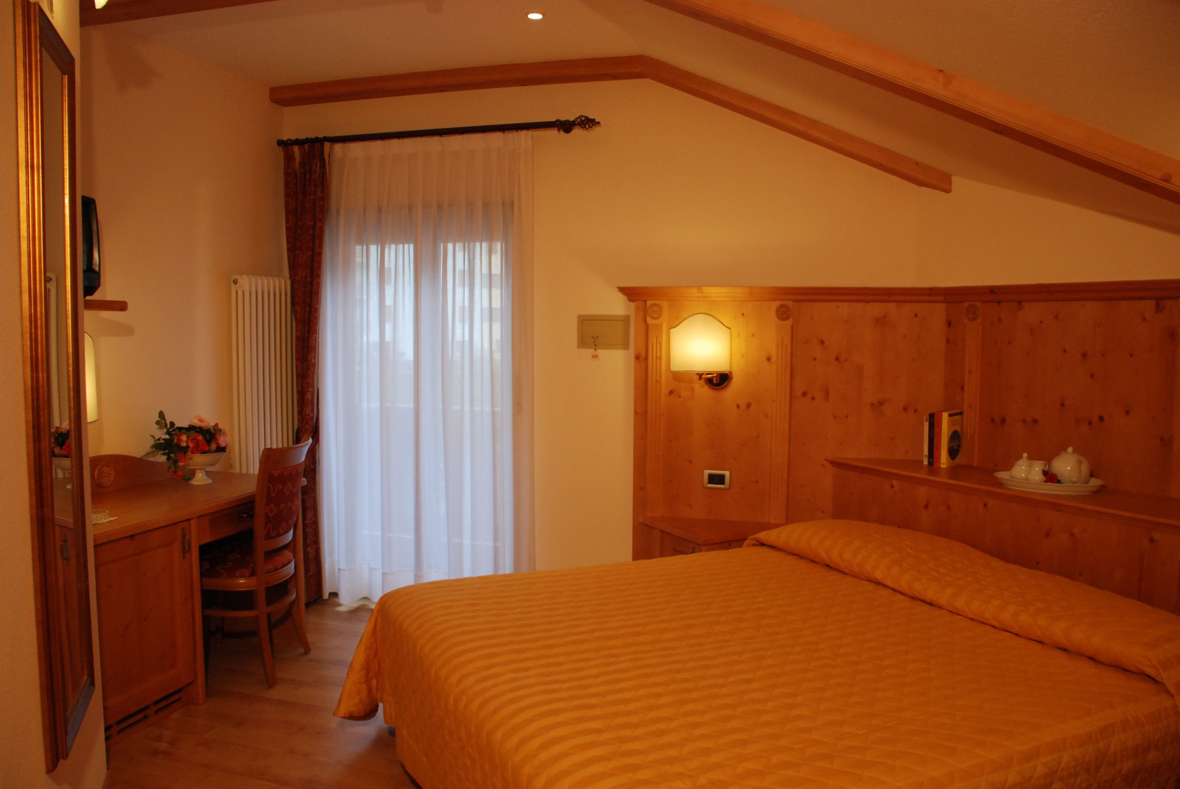 Un dormitorio con una cama de madera, un escritorio y una silla.