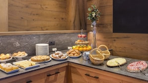 Un bufé con diversos alimentos, entre ellos pasteles, frutas y un pastel.
