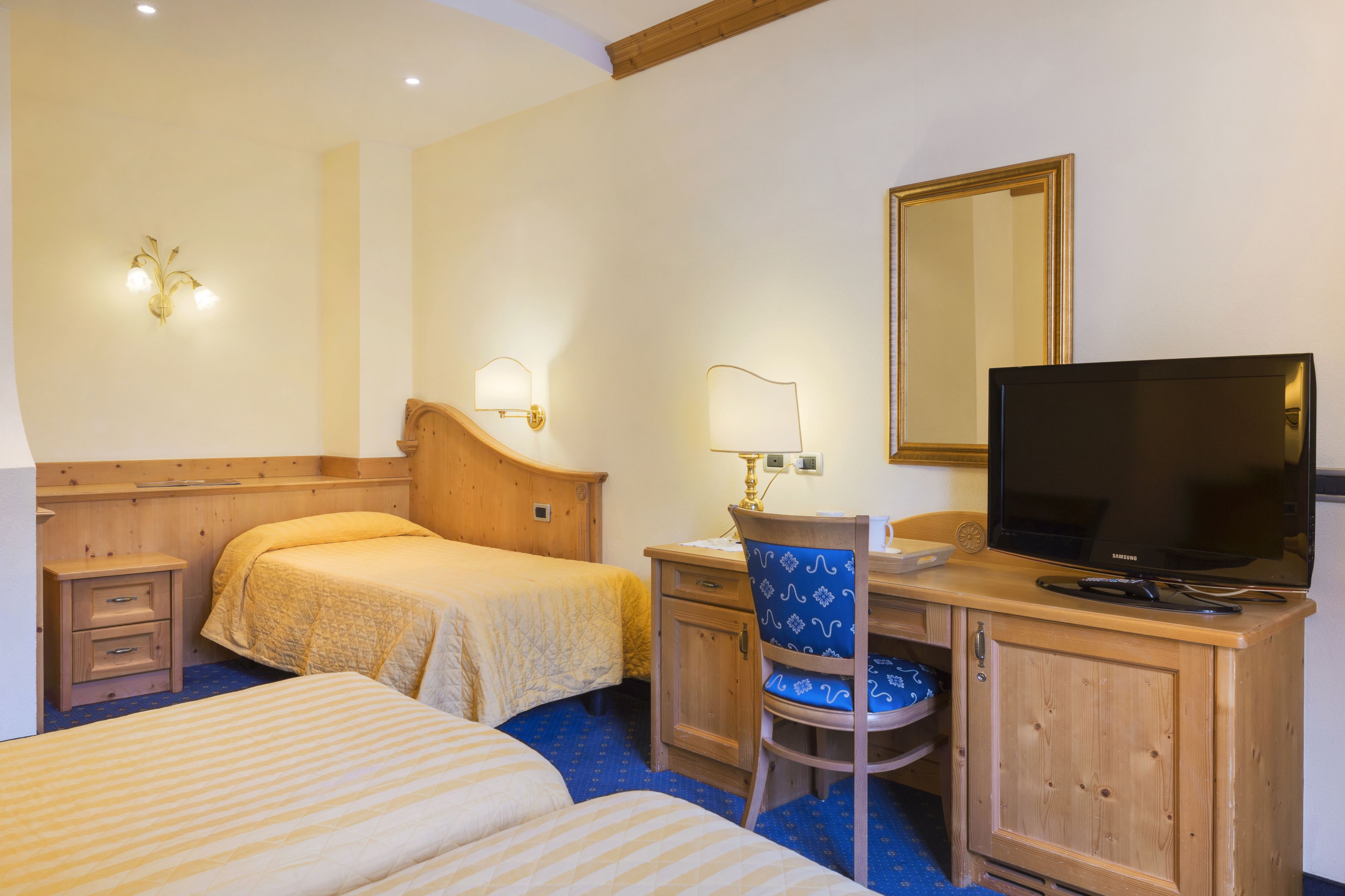 A hotel room with two beds, a desk with a chair, a television, and a mirror.