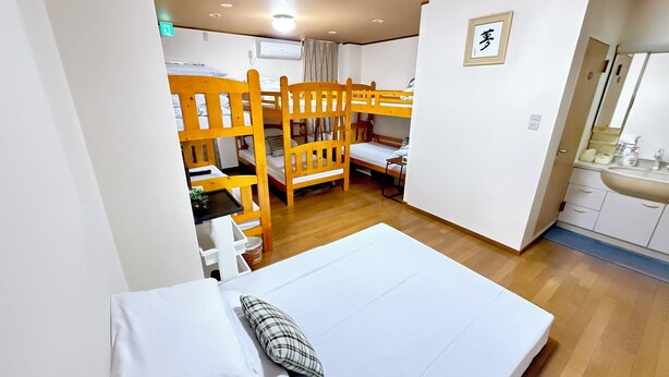 A dormitory room with bunk beds, a small kitchenette, and a bathroom. - Petit Hotel 017 (Tokushima)