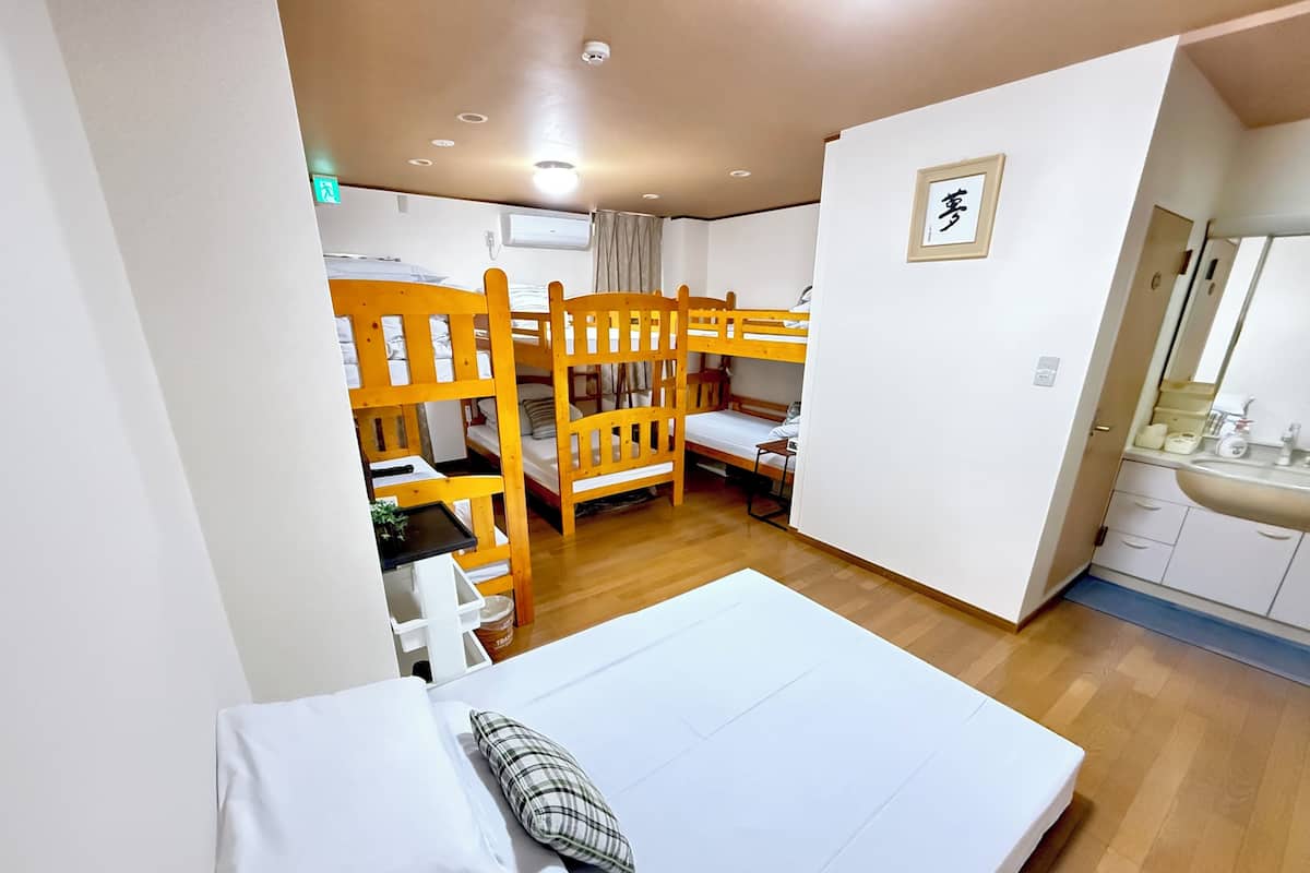 A dormitory room with bunk beds, a small kitchenette, and a bathroom.