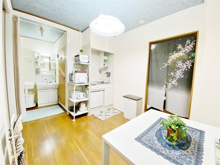 A compact kitchen with white appliances, a small dining table, and a decorative plant.