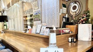 A hotel reception desk with a wooden counter, a clock, and various informational signs. - Petit Hotel 017 (Tokushima)