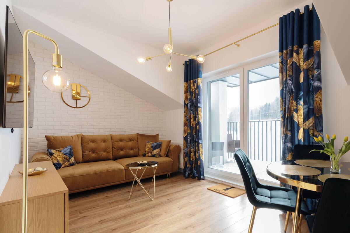 A modern living room with a sofa, a dining table, and a chandelier.