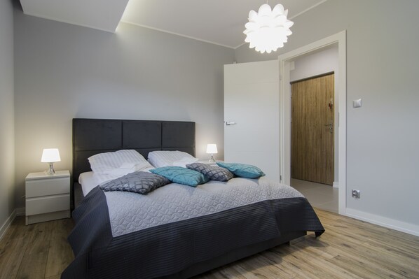 Un dormitorio moderno con cama, mesitas de noche y una puerta.
