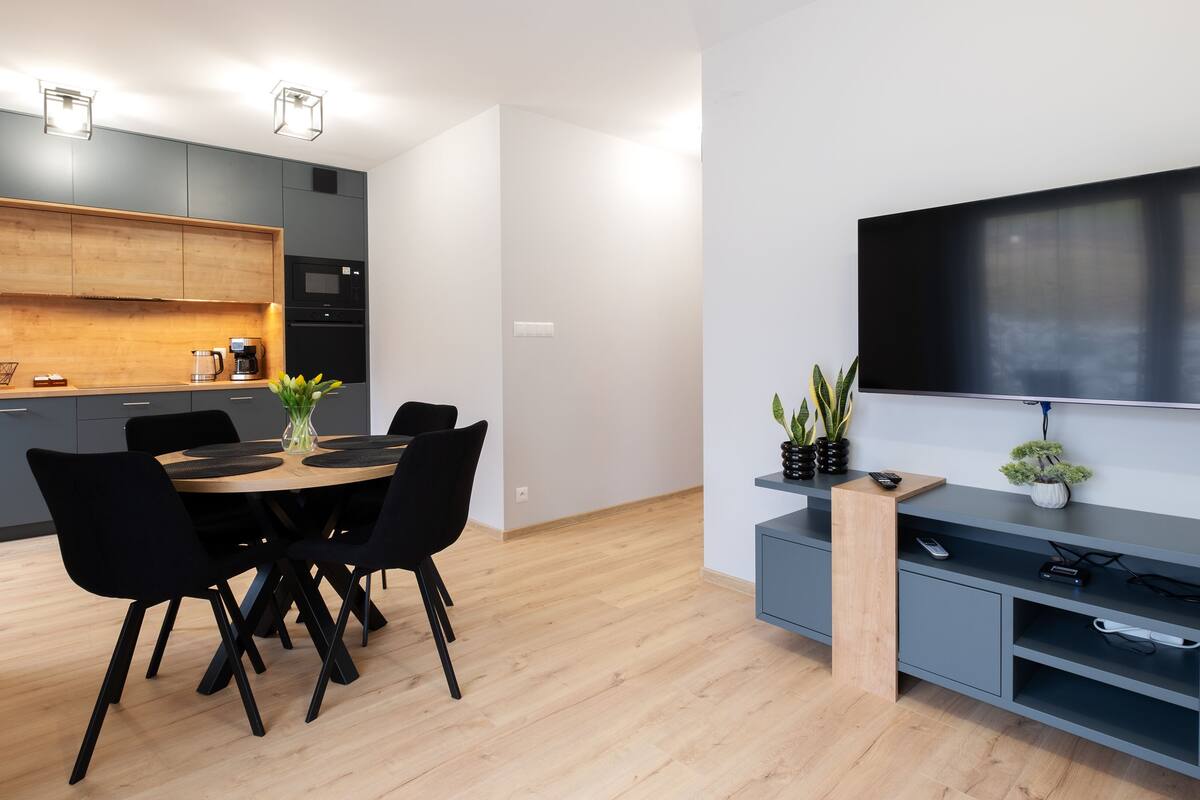 A modern kitchen with grey cabinets, a wooden countertop, and a built-in microwave.