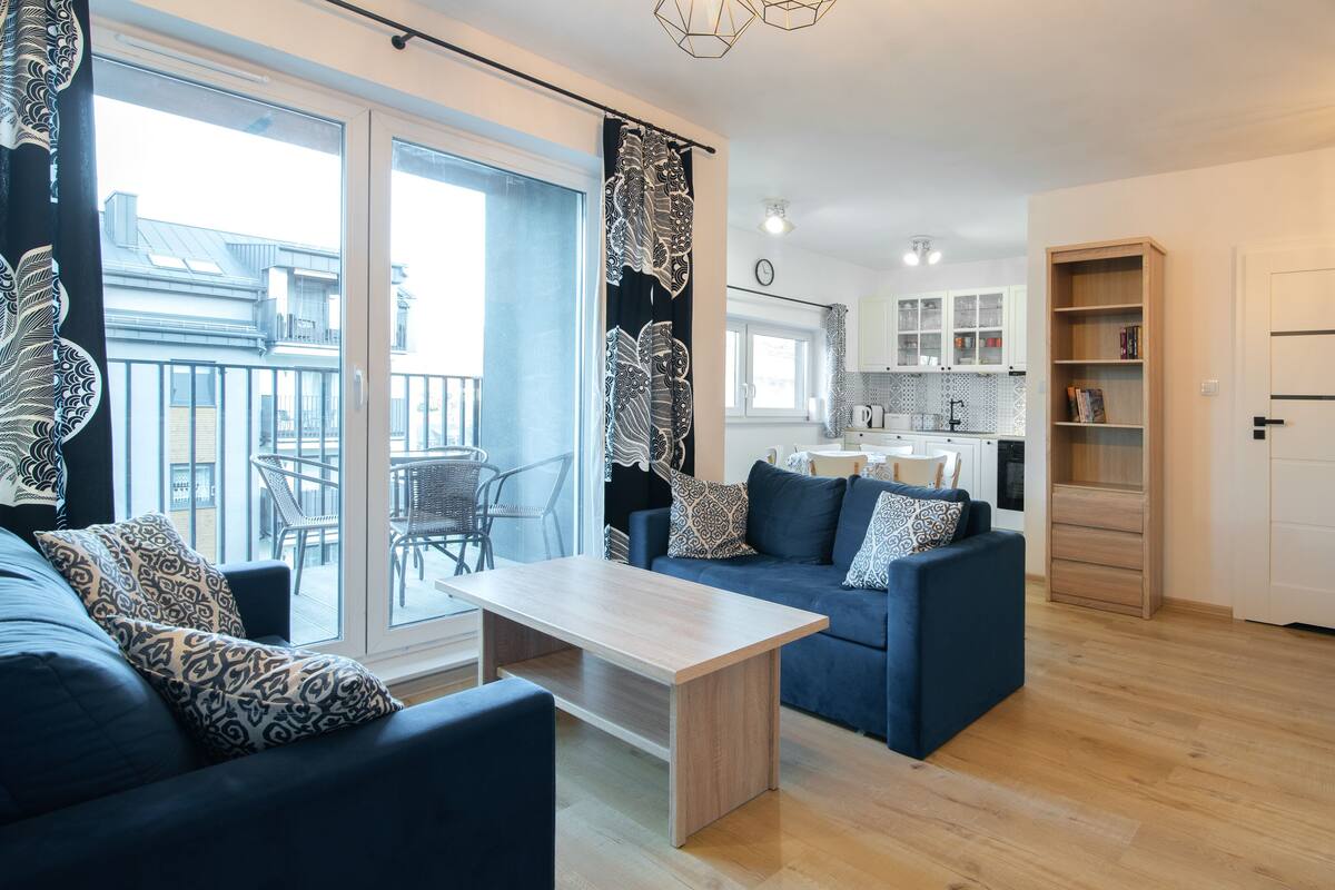 A modern living room with a sofa, a coffee table, and a dining area with chairs.
