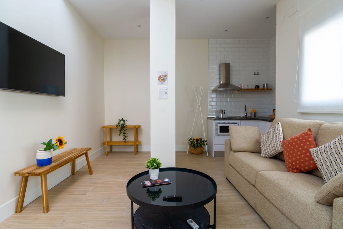 A modern living room with a sofa, a coffee table, a bench, and a TV.