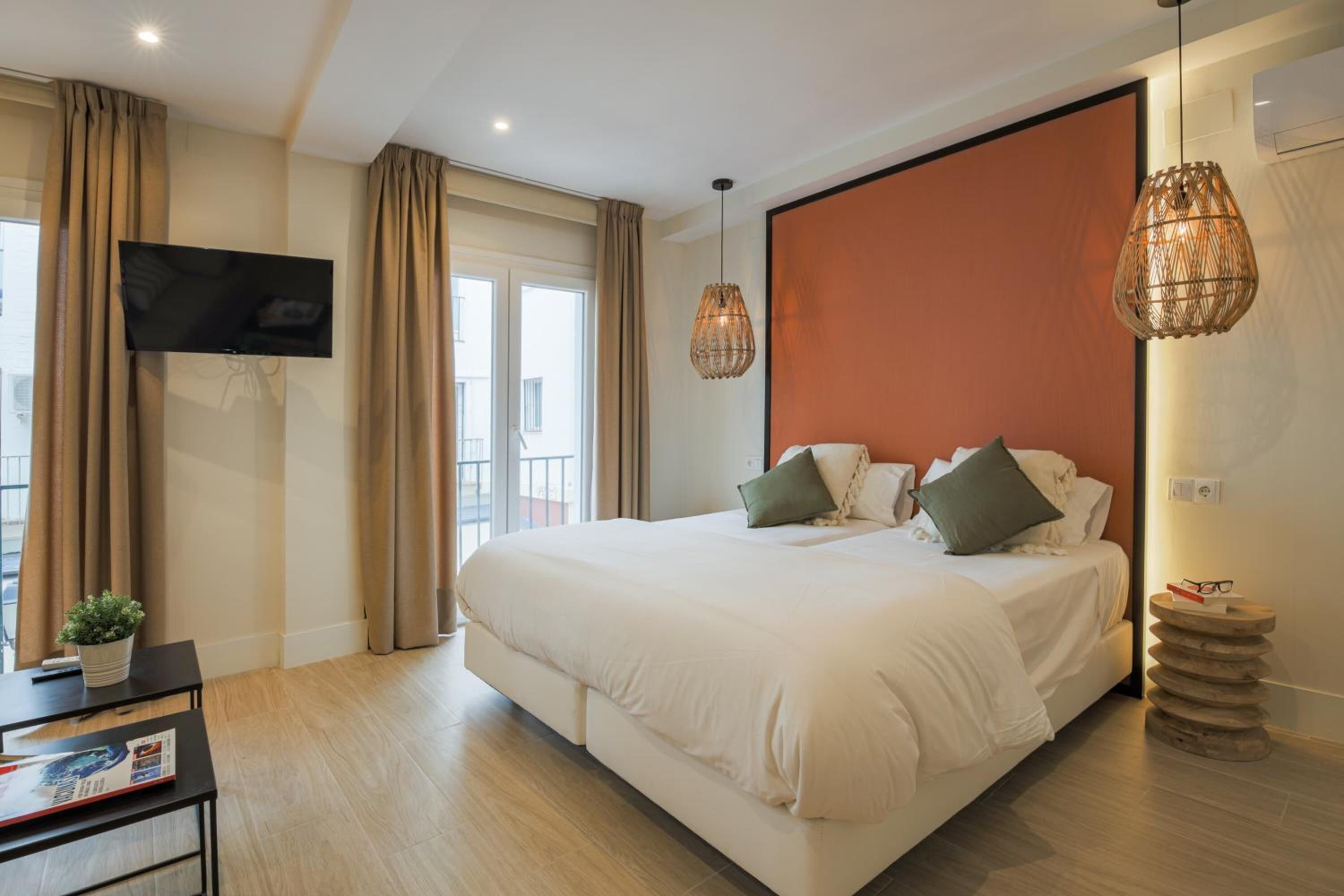 Een moderne hotelkamer met een groot bed, een flatscreen televisie, een kleine tafel met een plant en uitzicht op het omliggende landschap.