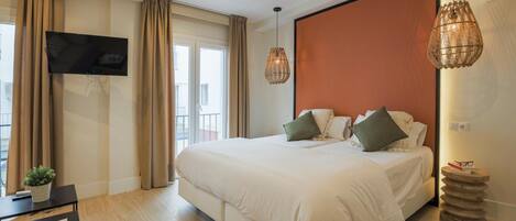 Een moderne hotelkamer met een groot bed, een flatscreen televisie, een kleine tafel met een plant en uitzicht op het omliggende landschap.