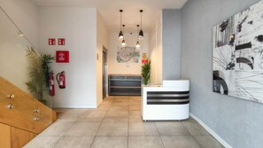 A modern reception area with a white desk, a map on the wall, and a fire extinguisher. - Apartamentos Magna Sevilla (Seville)