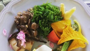Un plato con diferentes alimentos, como pan, verduras y un postre.