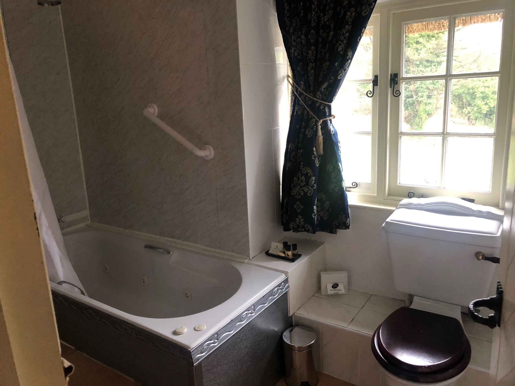 A bathroom with a bathtub, toilet, and window.