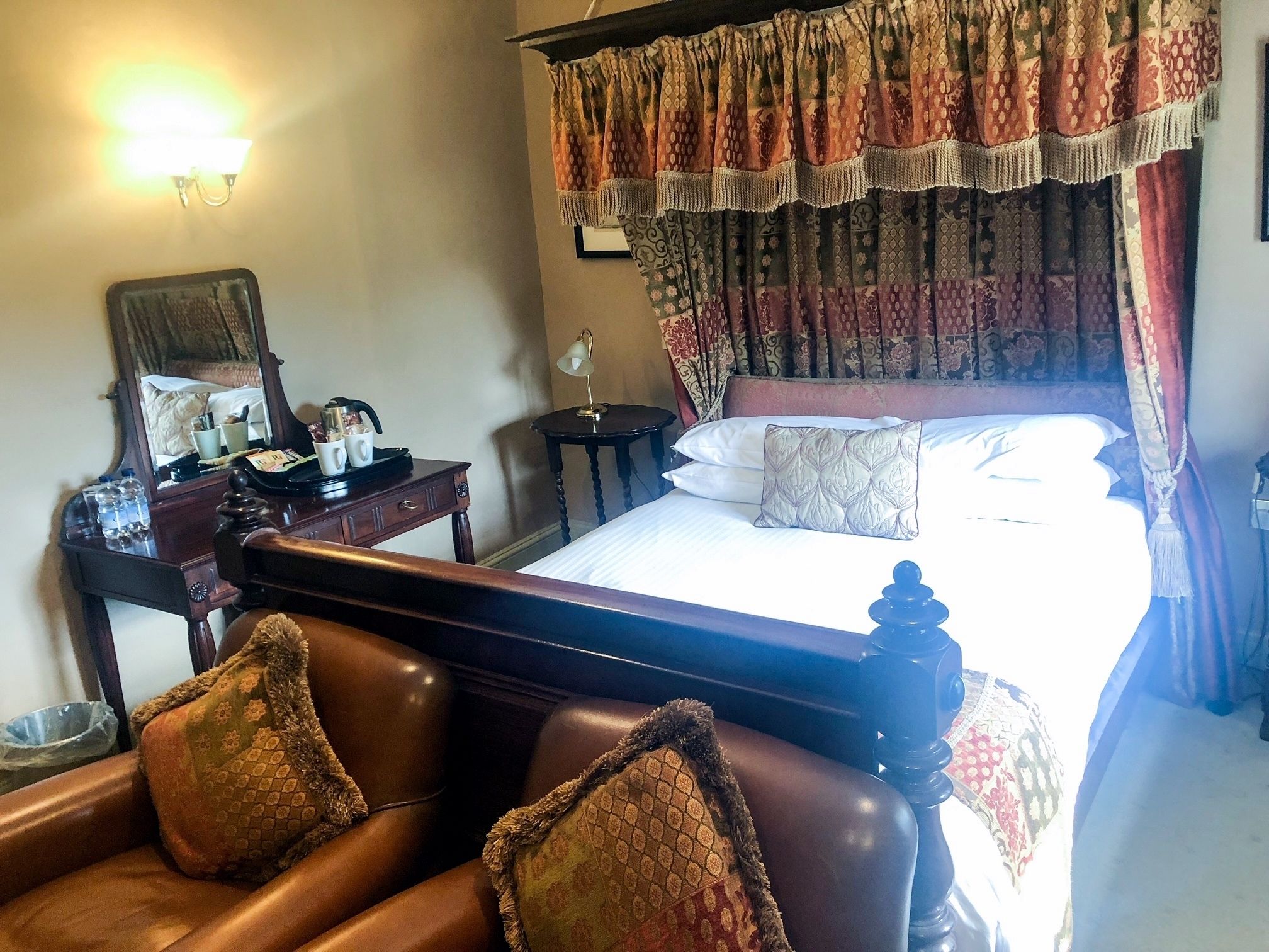 Une chambre d’hôtel avec un lit, un bureau, une chaise, une lampe et un miroir.