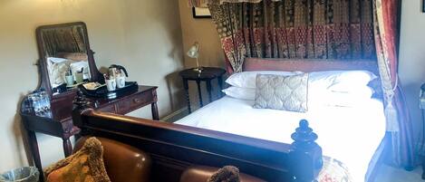 Une chambre d’hôtel avec un lit, un bureau, une chaise, une lampe et un miroir.