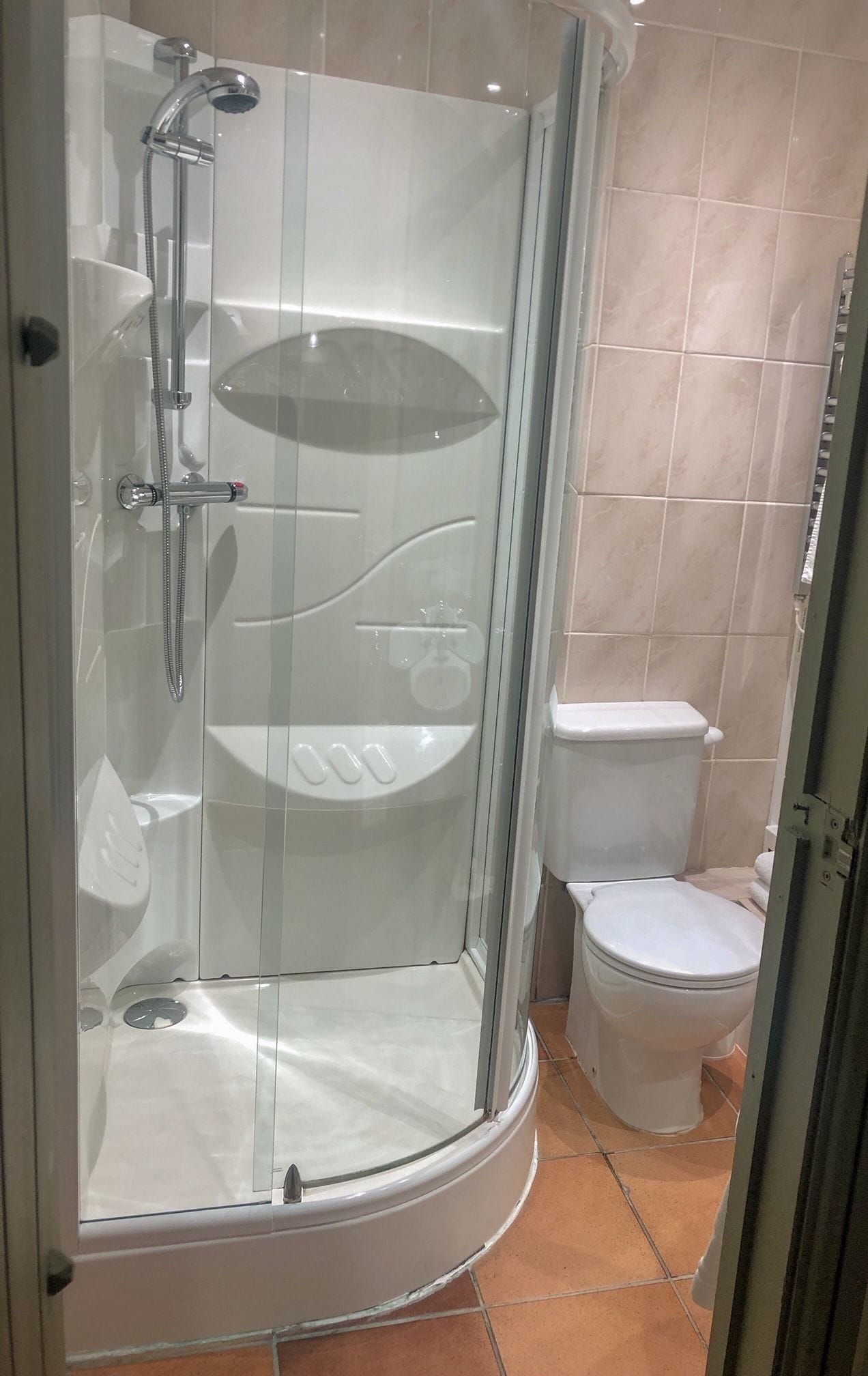 Une douche en verre, avec des toilettes et un lavabo blancs, dans une salle de bain.