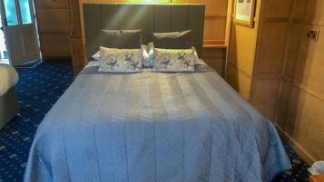 Habitación de hotel con una cama grande, cabecero y alfombra azul.