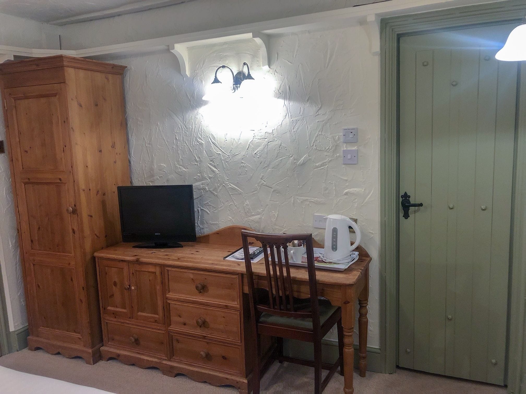 Une pièce comprenant un meuble en bois, un téléviseur, une chaise, une table et une porte.