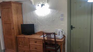 Une pièce comprenant un meuble en bois, un téléviseur, une chaise, une table et une porte.