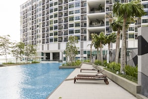 A modern hotel with a swimming pool, lounge chairs, and palm trees. - Luxury Suite Icity Shah Alam (Shah Alam)