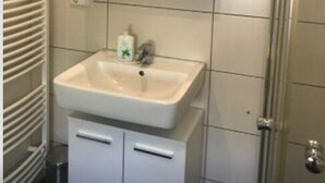 A bathroom with a white sink, a mirror, and a shower. - Oftersheim Apartment (Oftersheim)