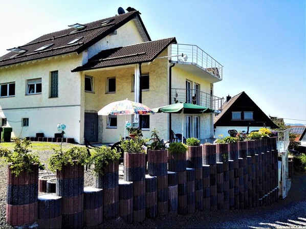 A two-story building with a balcony and a patio area with outdoor seating.