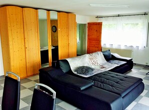 A modern room with a black sofa, a wooden wardrobe, and a dartboard.