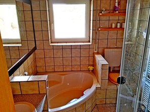 A bathroom with a bathtub, a toilet, and a shower area.