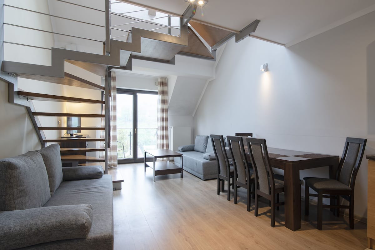 Un moderno apartamento tipo loft con una escalera, un comedor, un sofá y una cocina.