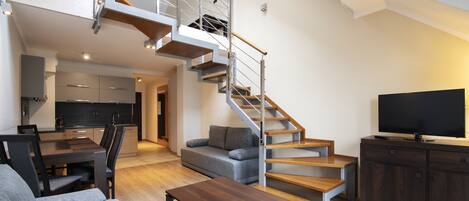 A modern living room with a staircase, a dining area, and a kitchen.