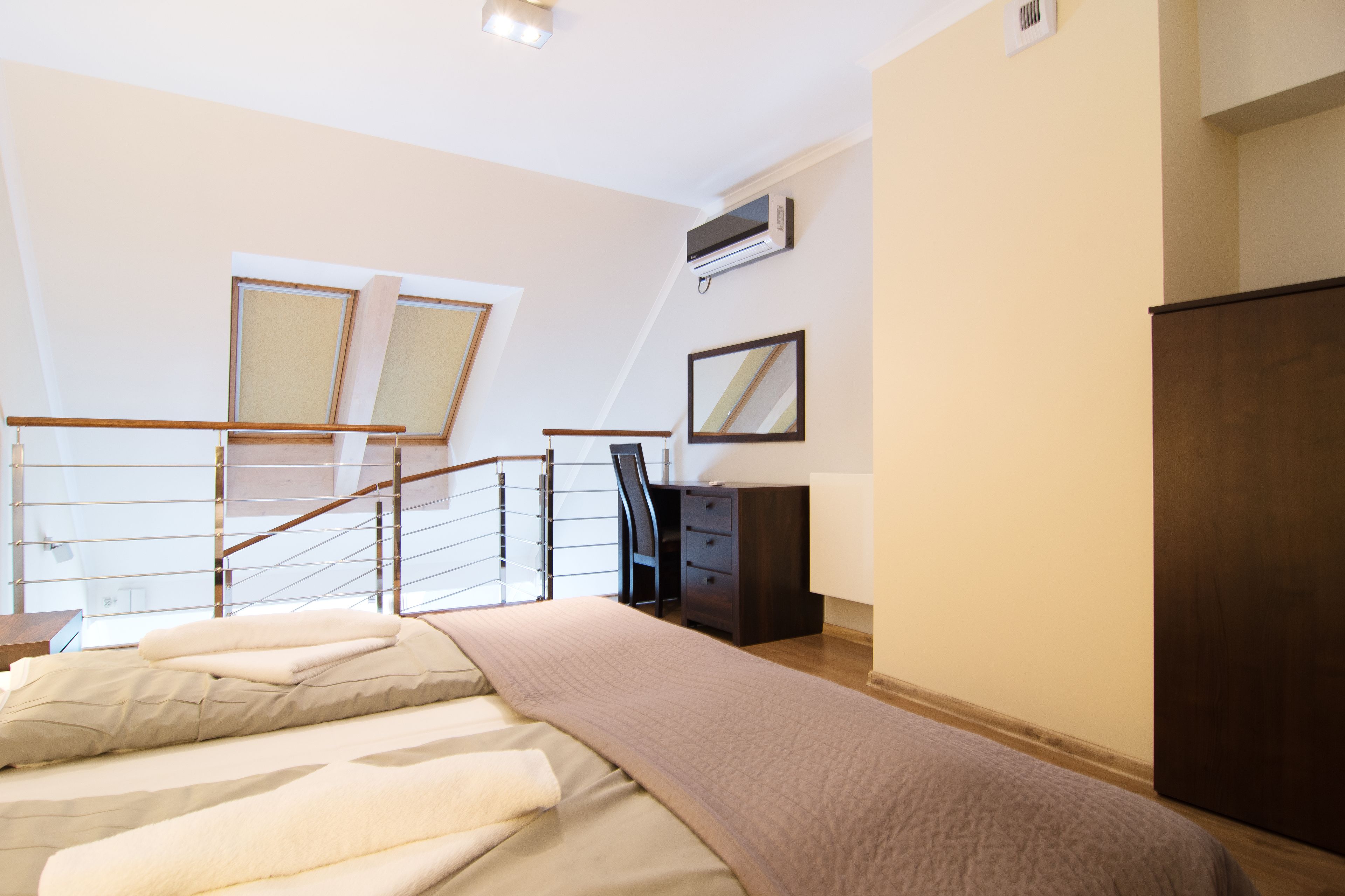 Une chambre à coucher comprenant un lit, un bureau, une commode, un miroir et un escalier.