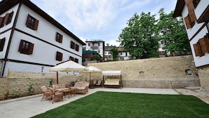 Ein Innenhof mit Steinmauern, Gartenmöbeln und Sonnenschirmen.
