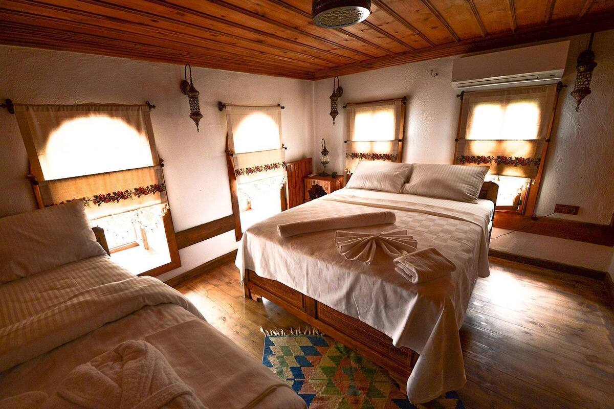 Une pièce chaleureuse avec deux lits, des poutres en bois et un tapis à motifs.