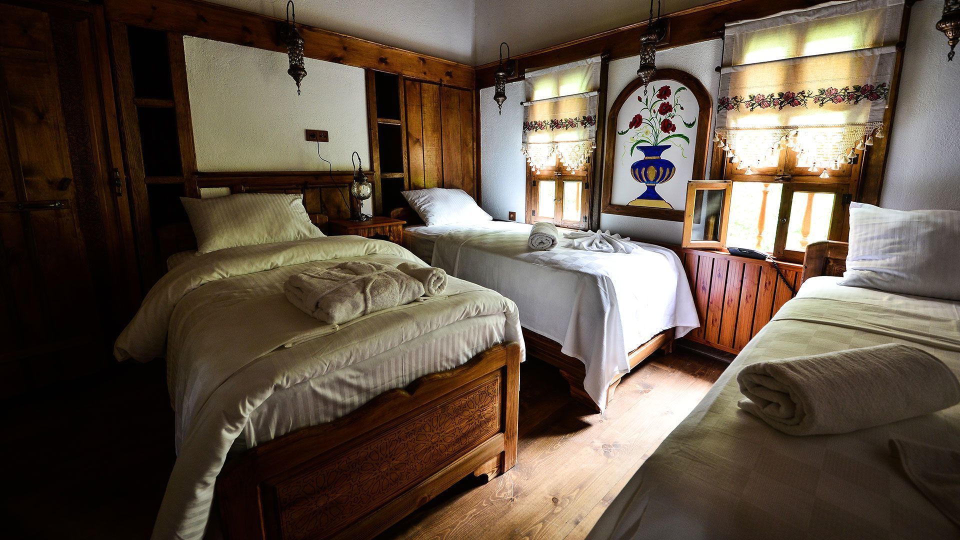 A traditional room with two wooden beds, a wooden dresser, and a decorative mirror.