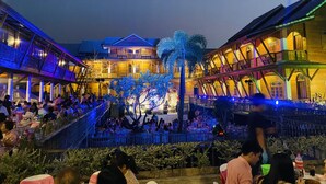 A courtyard with multiple dining areas, a central stage, and a large tree.
