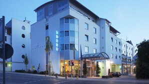 Um hotel moderno com fachada curva, grandes janelas e uma entrada destacada com cobertura de vidro.