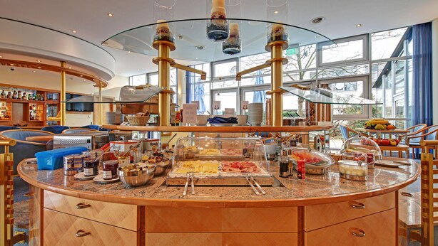 Uma área de buffet com diversos alimentos e um espaço de refeições com cadeiras e mesas.
