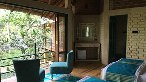 Quarto com varanda, cama, cadeira, mesa pequena e espelho.