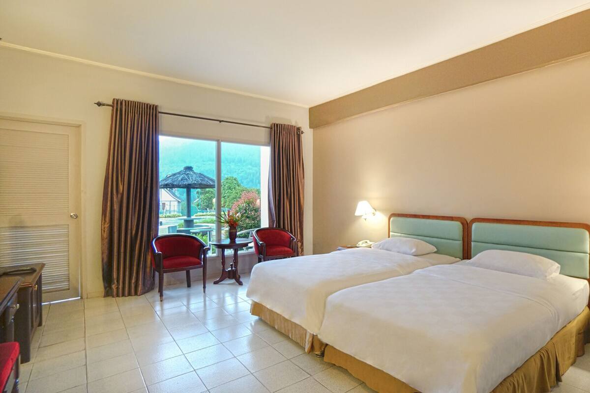 A hotel room with two beds, a desk, and a chair.