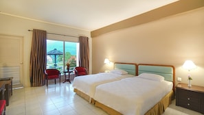 A hotel room with two beds, a desk, and a chair.