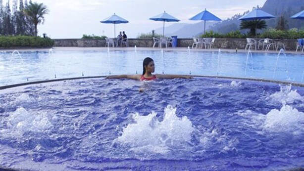 A pool with water jets, surrounded by lounge chairs and umbrellas. - Niagara Hotel Lake Toba & Resorts (Parapat)