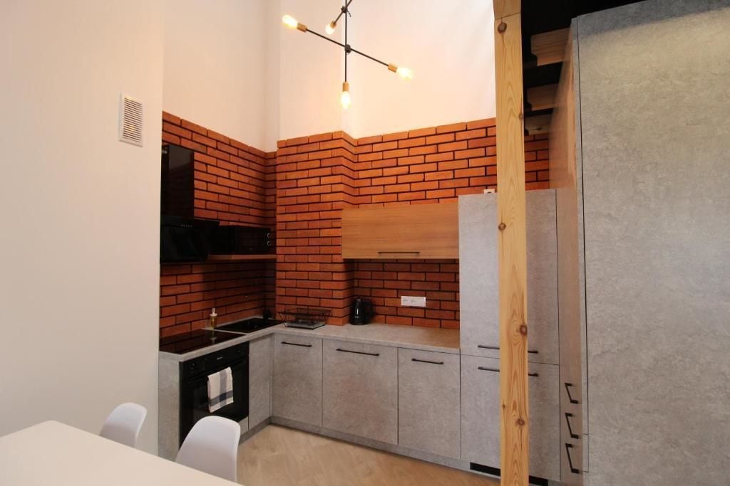 A compact kitchen with a brick backsplash, a built-in stove, and a wooden cabinet.