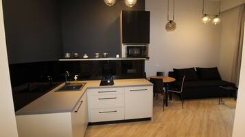 Een moderne keuken met een centraal eiland, een zithoek met een zwarte bank en hanglampen.