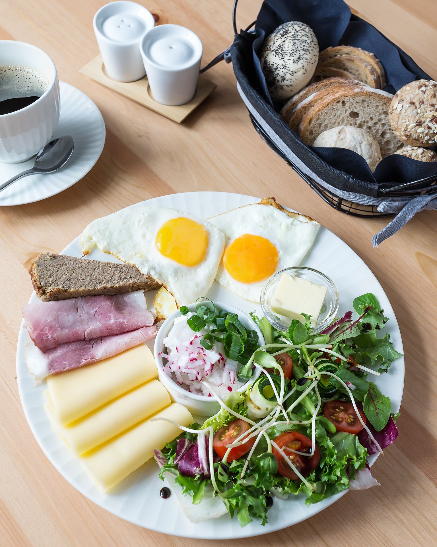 Un plato de desayuno con huevos, jamón, queso y ensalada.
