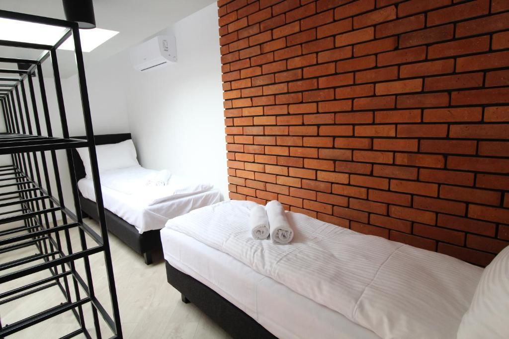 A hotel room with a brick accent wall, a bunk bed, and a single bed with rolled towels.