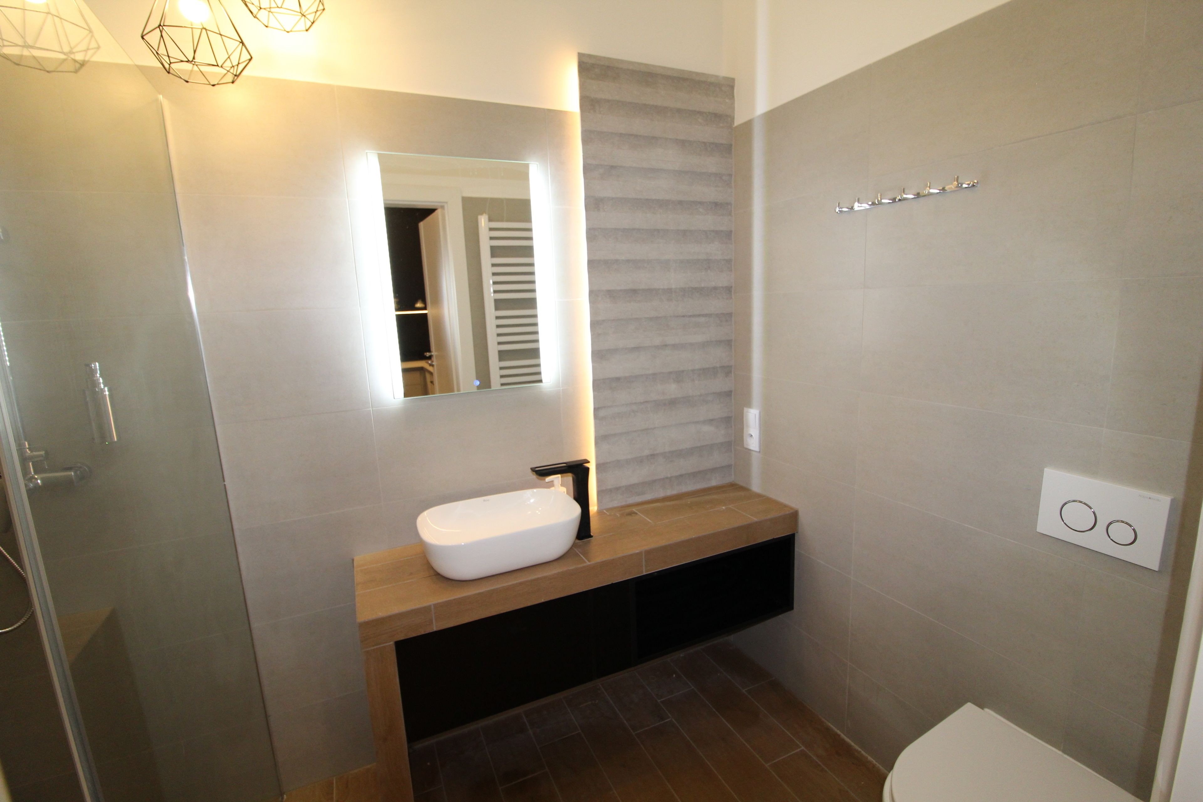 A modern bathroom with a white sink, a mirror, and a towel rack.