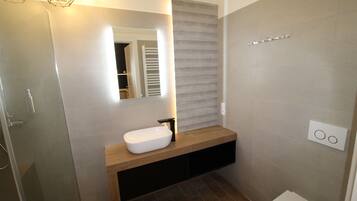 A modern bathroom with a white sink, a mirror, and a towel rack.